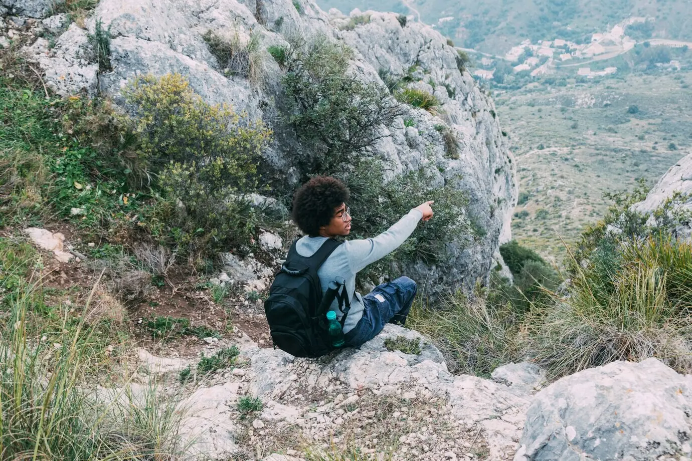 Ein Mann sitzt in der Natur auf einem Felsen.